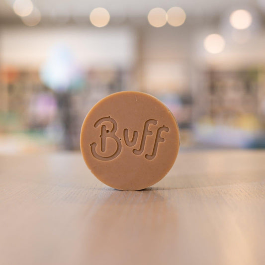 Rhassoul Clay Face Bar by Buff City Soap on wooden surface with blurred background